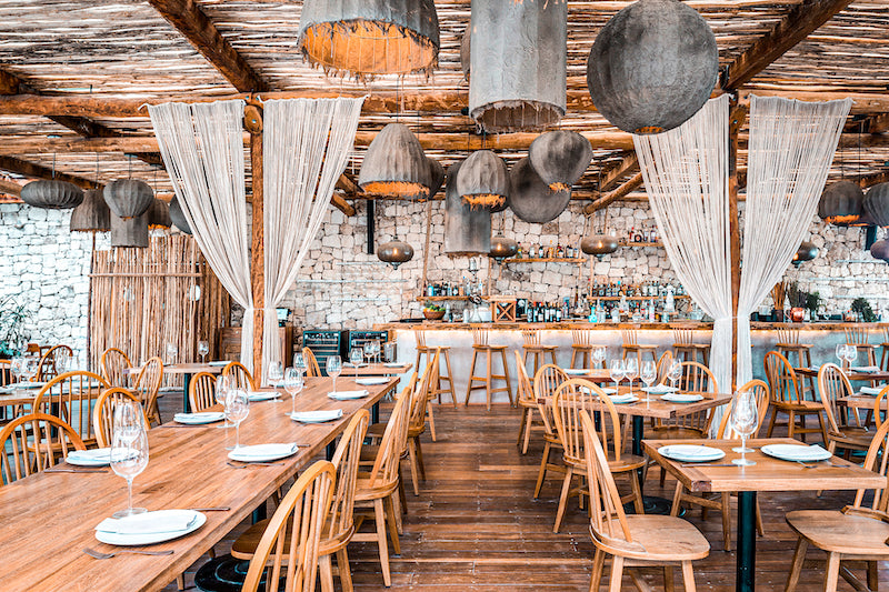 Rustic Taboo Beach Club restaurant with wooden tables, woven pendant lamps and macrame curtains