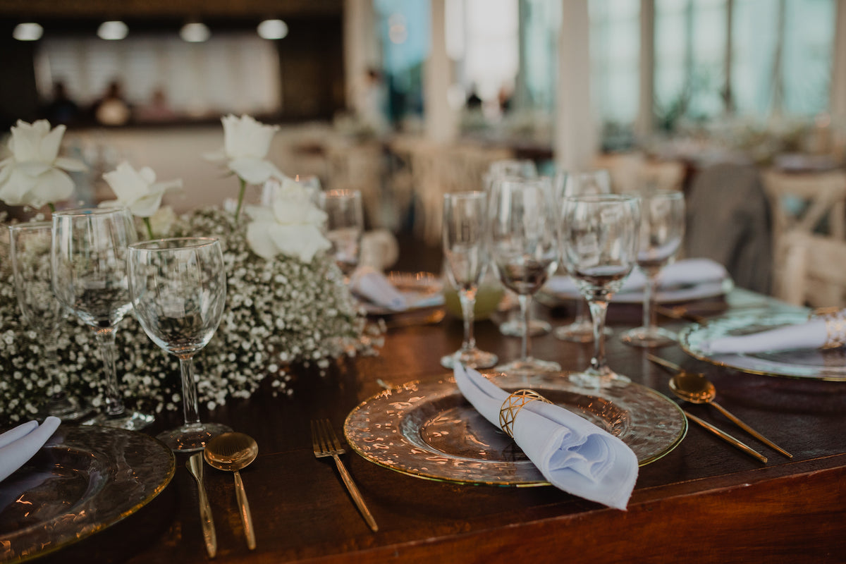Elegant wedding table setting with wine glasses, gold flatware, and baby's breath centerpieces captured by DreamArt