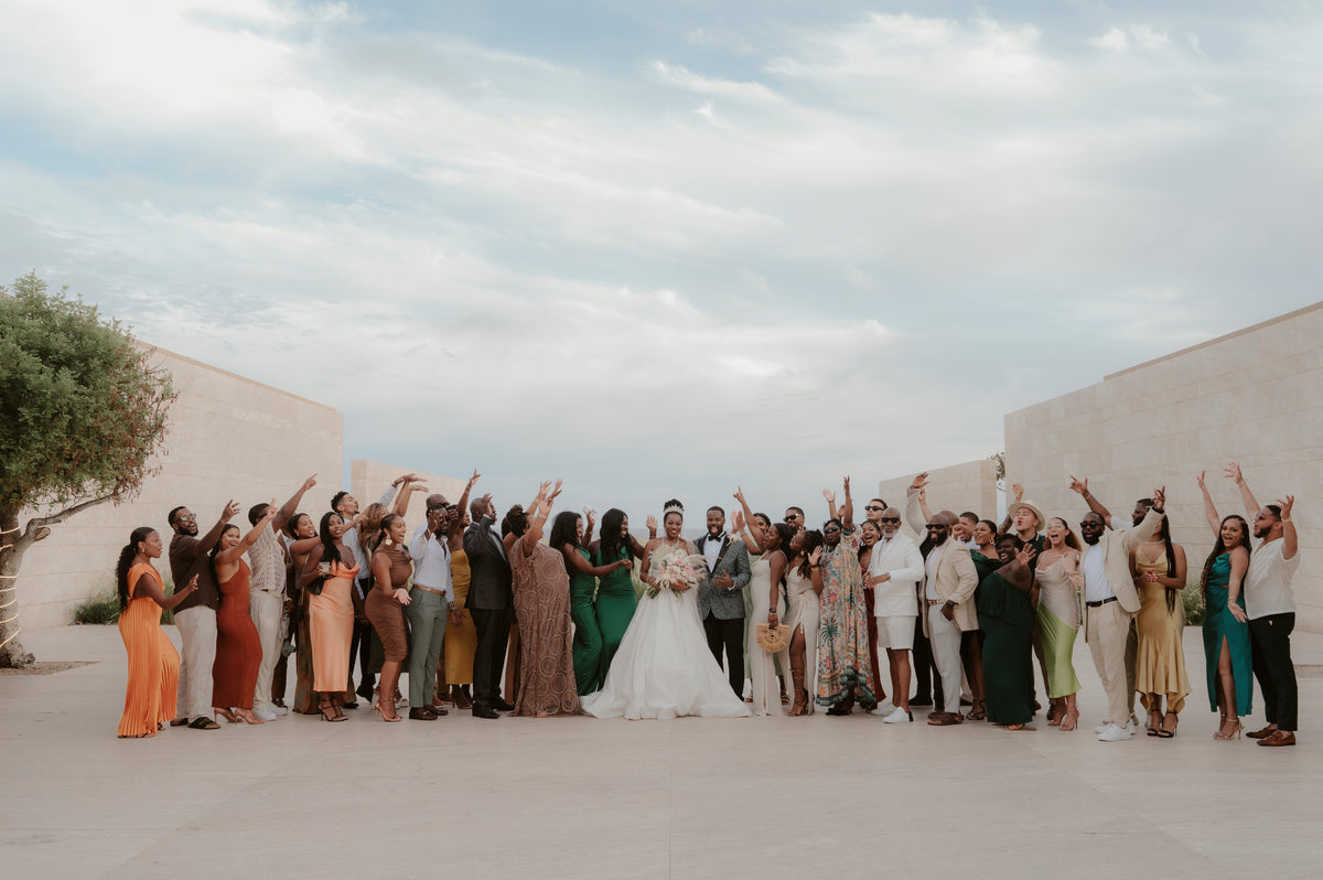 Bride and groom with a large group of cheering guests on an oceanfront terrace