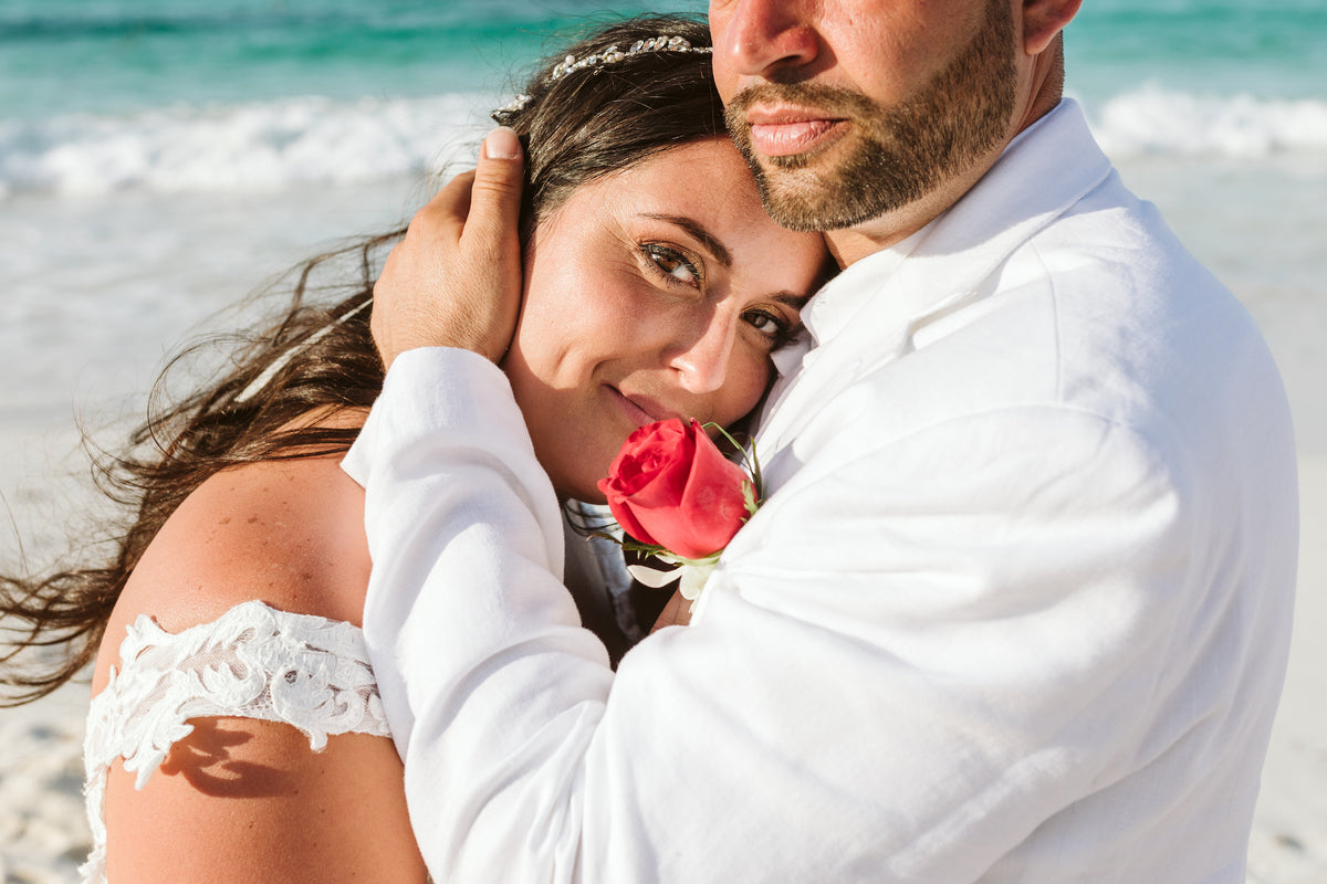 A bride and groom embrace on the beach at Grand Fiesta Americana Coral Beach Cancún, ocean waves behind them