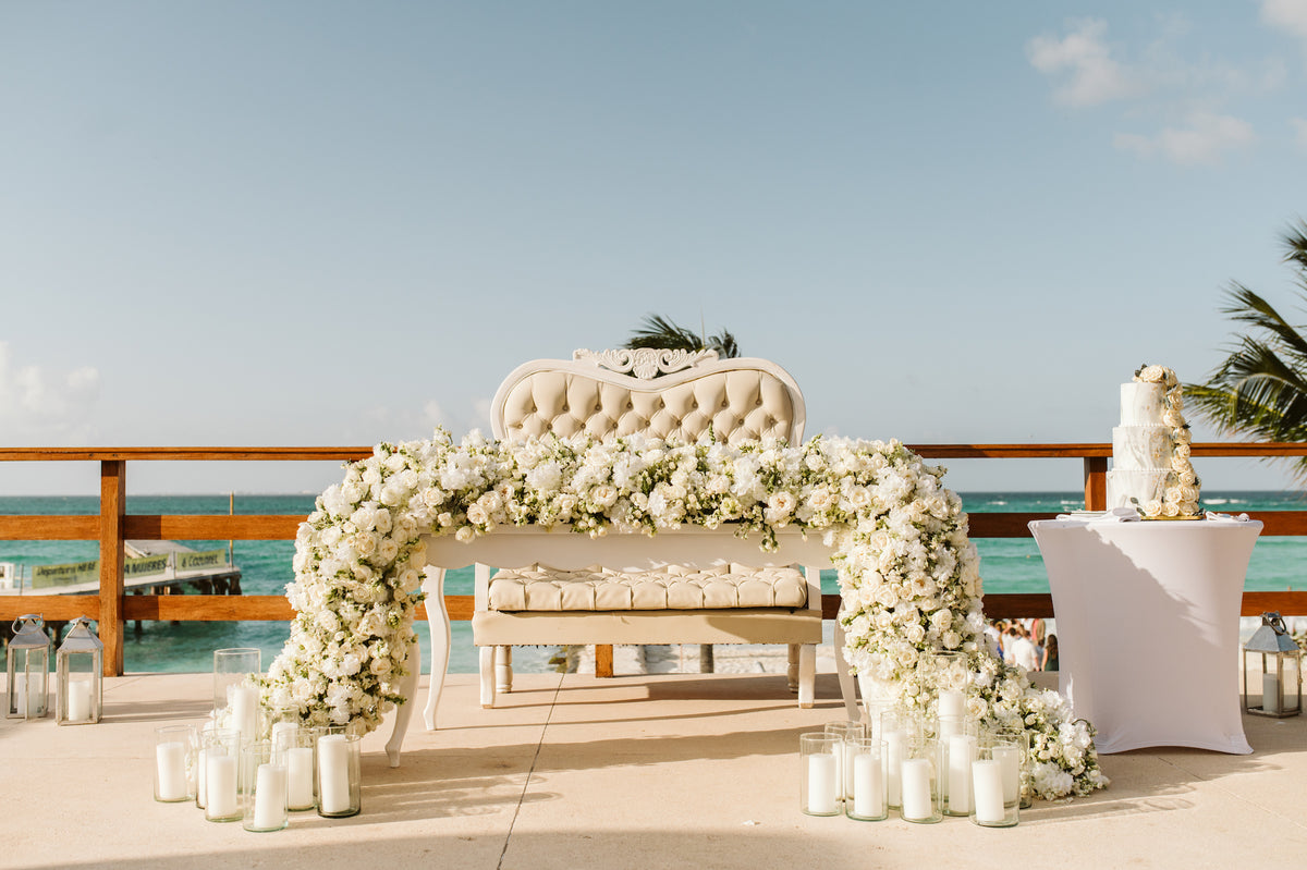 A tufted loveseat draped in white floral garland overlooks the ocean at Grand Fiesta Americana Coral Beach Cancún