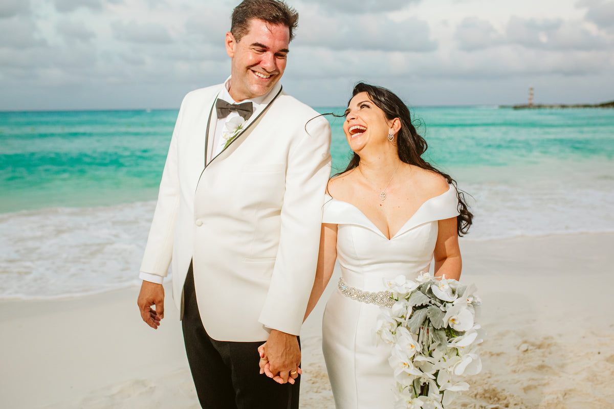 Bride and groom laughing and holding hands on the beach at Grand Fiesta Americana Coral Beach Cancún