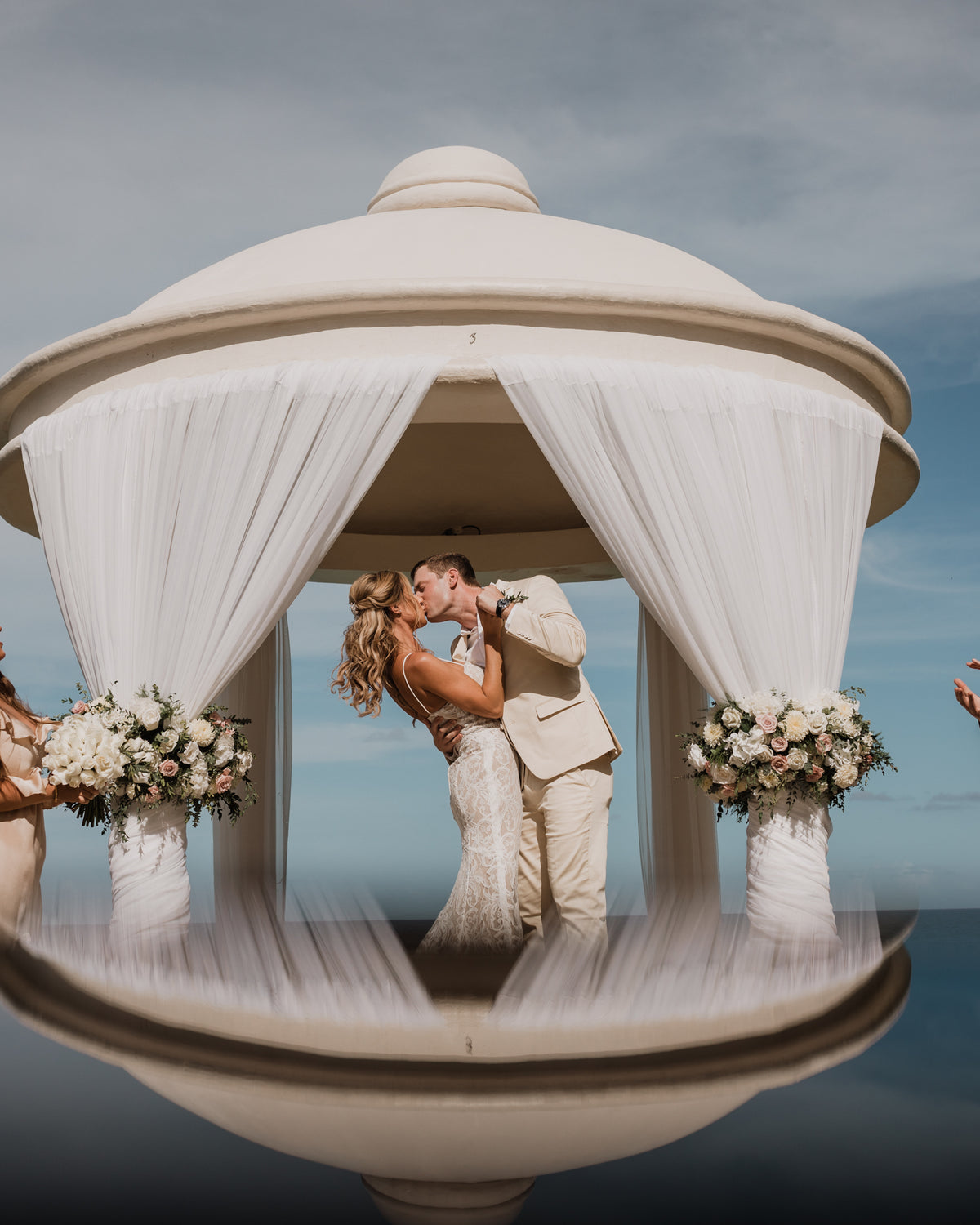 Bride and groom kissing under a domed white gazebo with floral columns at JW Marriott