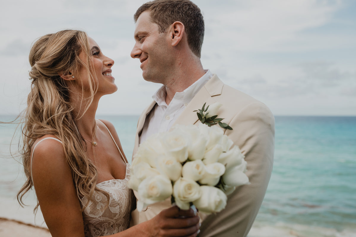 Bride and groom smiling face to face on a beach at JW Marriott, ocean visible behind them