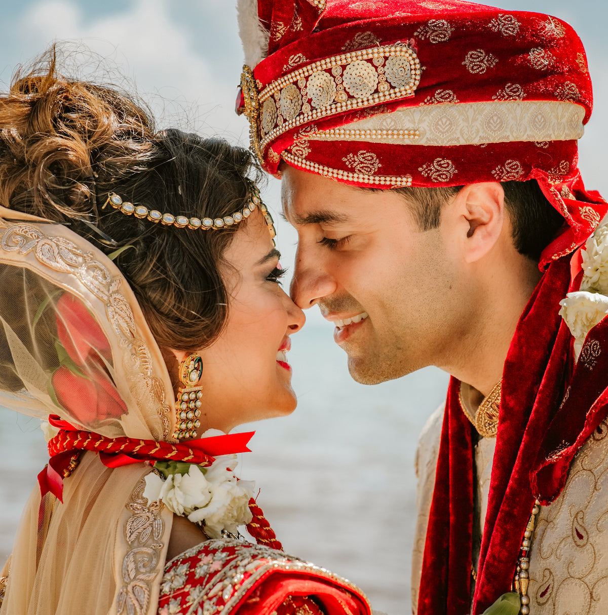 Bride and groom in traditional Indian wedding attire face closely, foreheads nearly touching, at Moon Palace Cancún