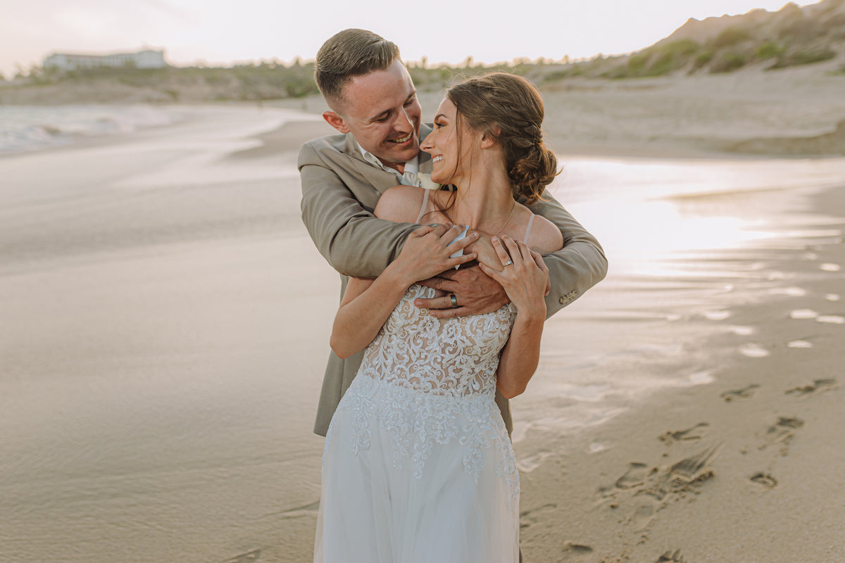 A bride and groom embrace on the beach at Marquis Los Cabos, Mexico, at sunset