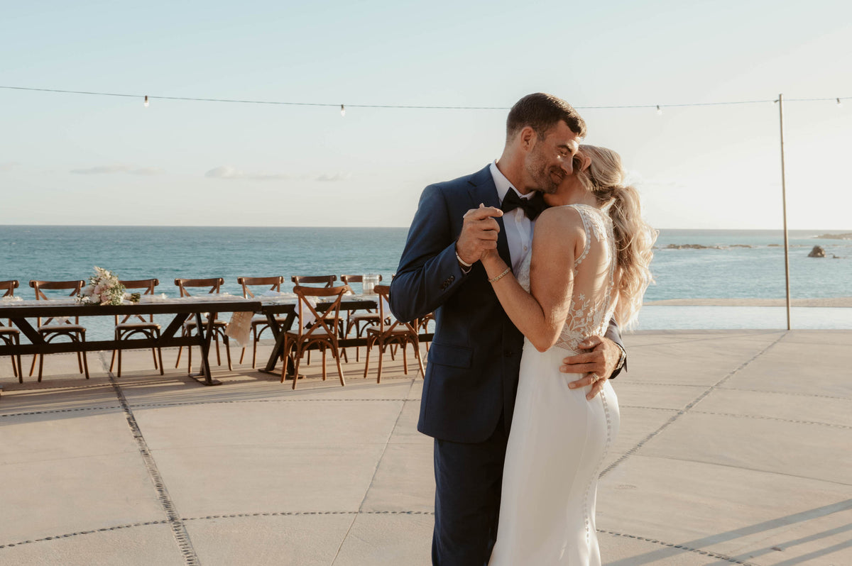 Bride and groom slow dancing on a terrace overlooking the ocean at Marquis Los Cabos
