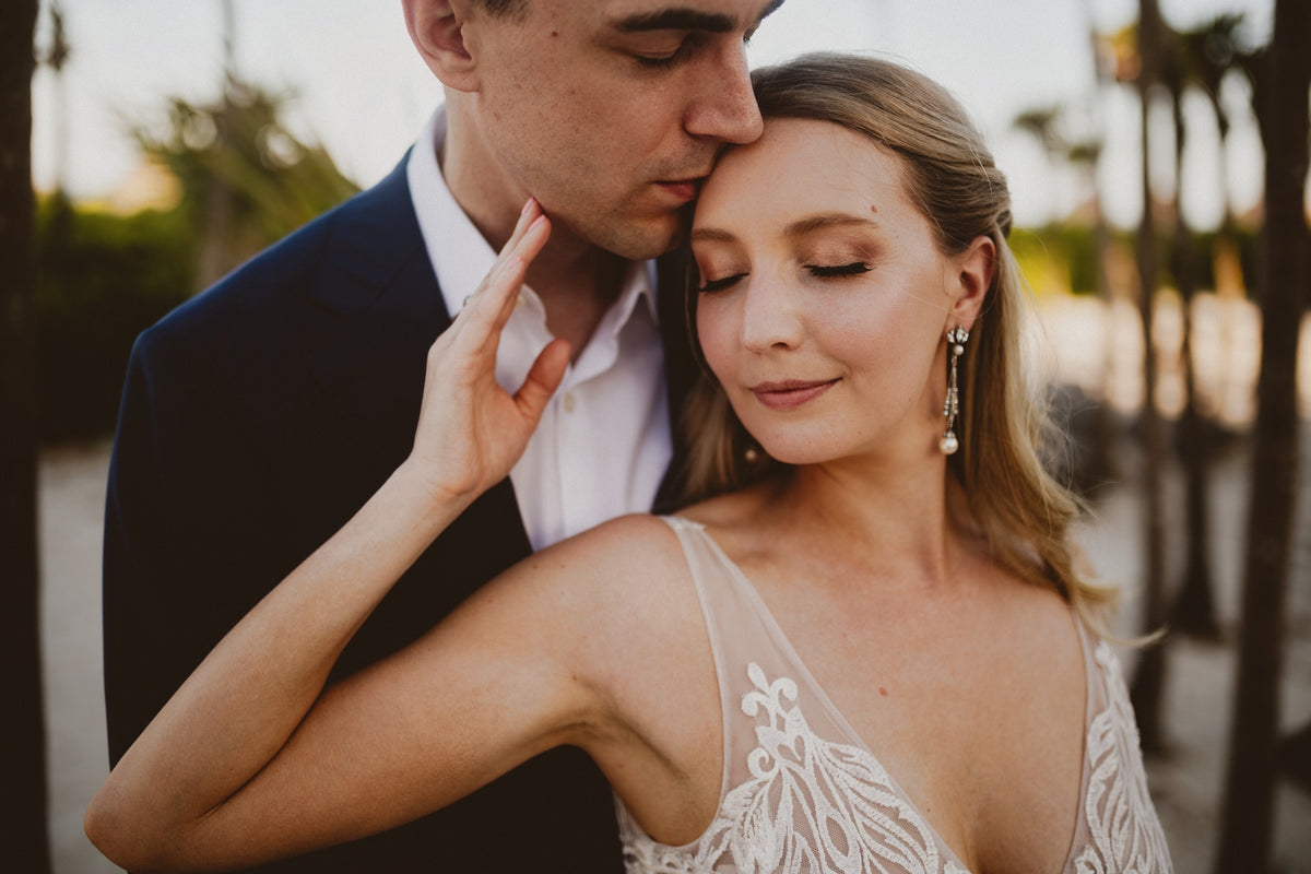 Bride with closed eyes rests her forehead against a groom's face at Valentin Imperial Riviera Maya