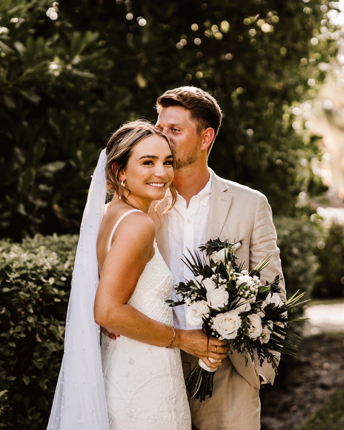 Bride and groom embracing outdoors with white bouquet
