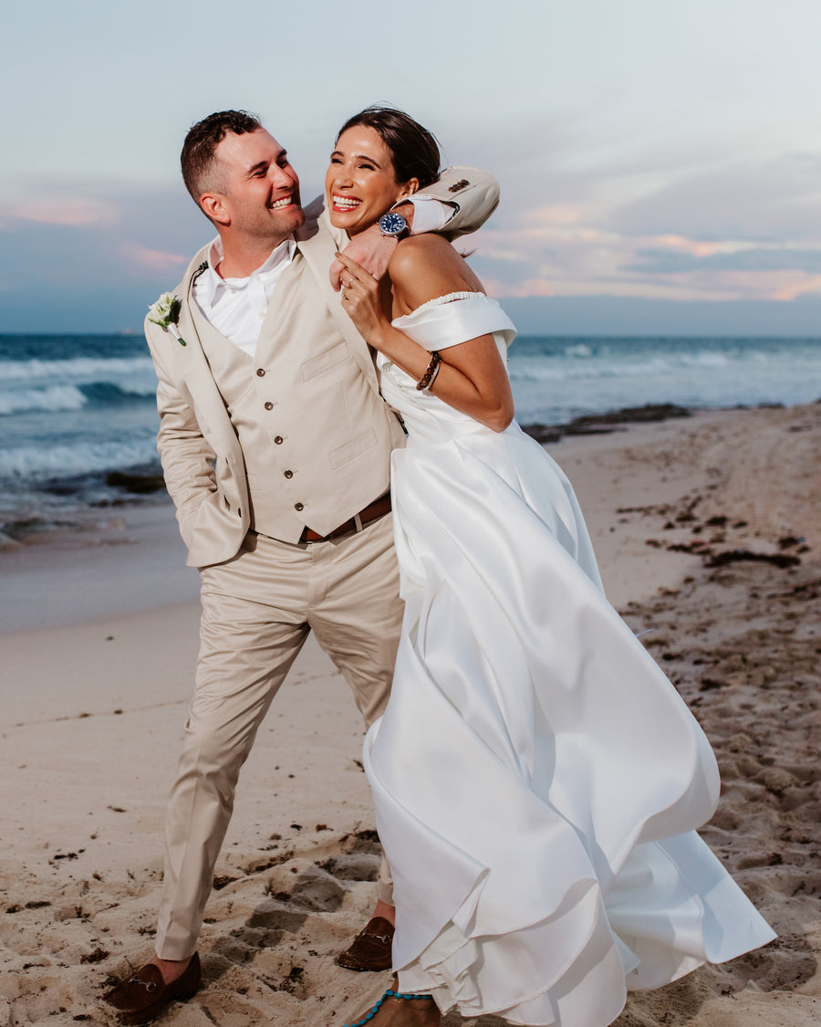 Bride and groom laughing together on the beach at Valentin Imperial Riviera Maya, Mexico