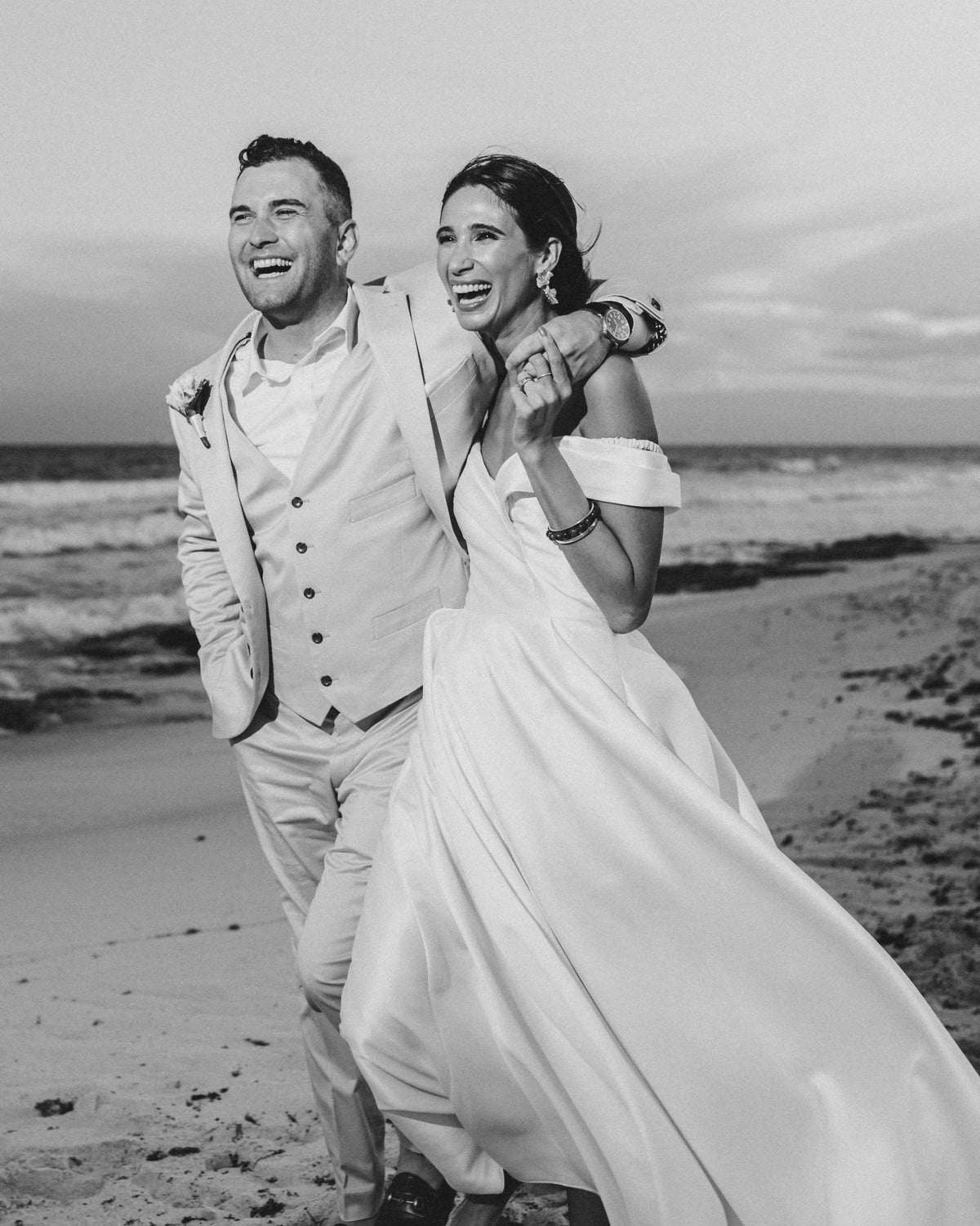 Black and white photo of a bride and groom laughing together on the beach at Valentin Imperial Riviera Maya