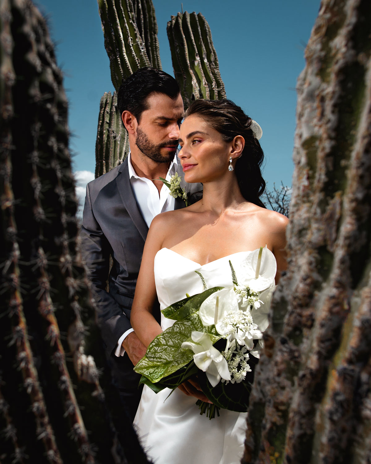 Bride with a white calla lily bouquet and groom posing among tall cacti at Le Blanc Los Cabos