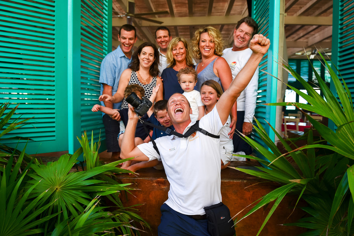 Laughing photographer takes a selfie with a cheerful multigenerational family under teal shutters in Cancun
