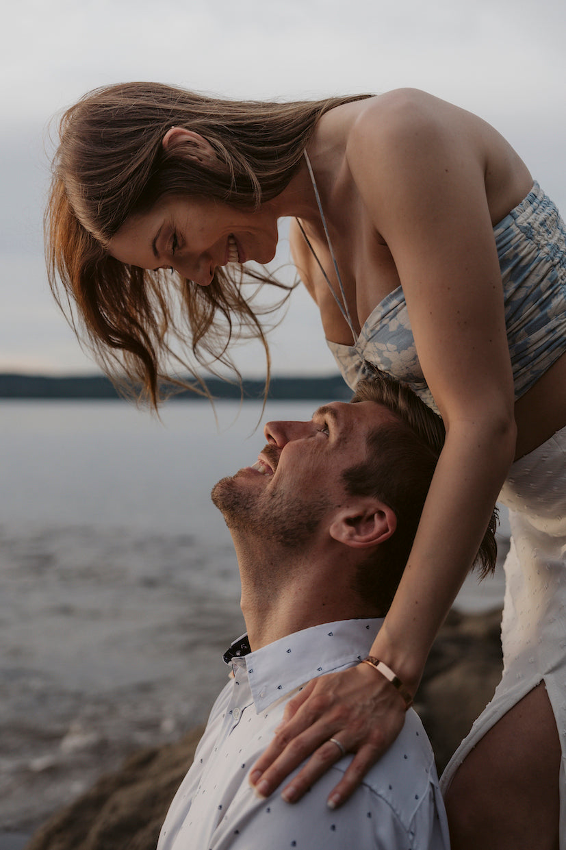 Woman leans down to smile at her partner by the water during a couples photoshoot in Guanacaste