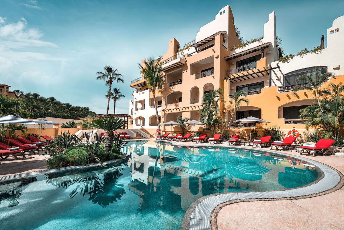 Pool and terracotta-colored hotel buildings with red loungers at a Mexican resort