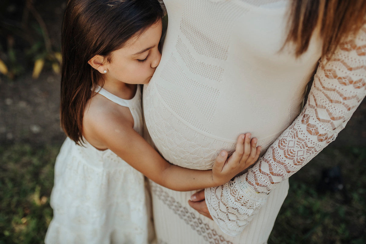 girl kissing belly of her mother