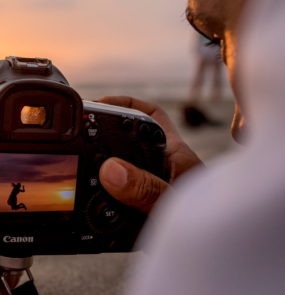 DreamArt photographer checks a sunset beach shot of a jumping woman on the camera screen