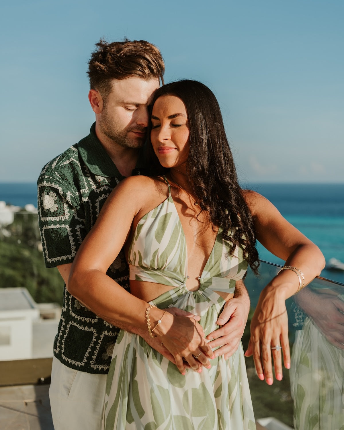 Couple embracing with eyes closed on an ocean-view terrace during a vacation photoshoot