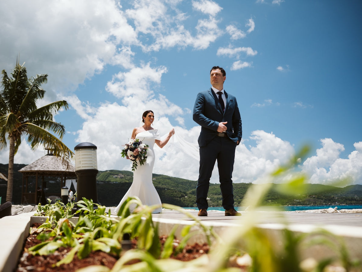 Bride walks toward her groom for their first look on an ocean-view terrace on their wedding day