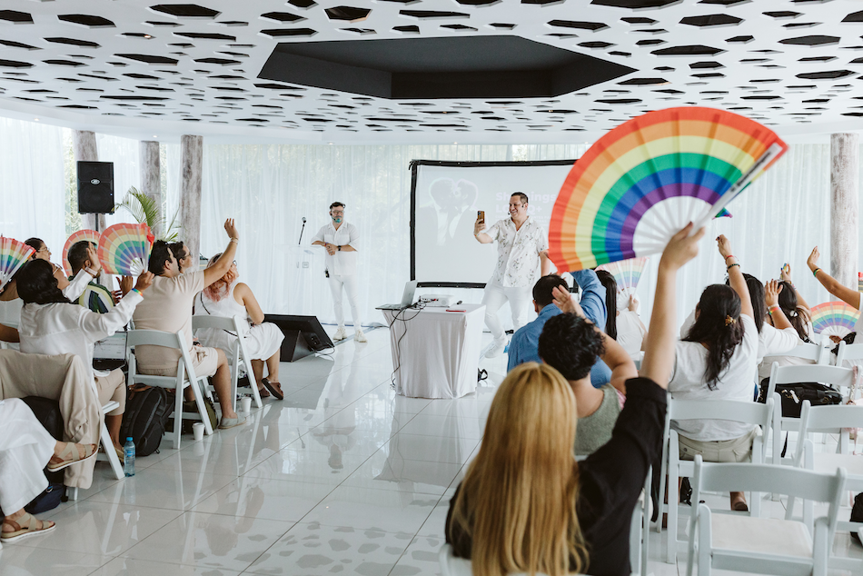 Attendees wave rainbow fans during a queer weddings certification workshop for photographers