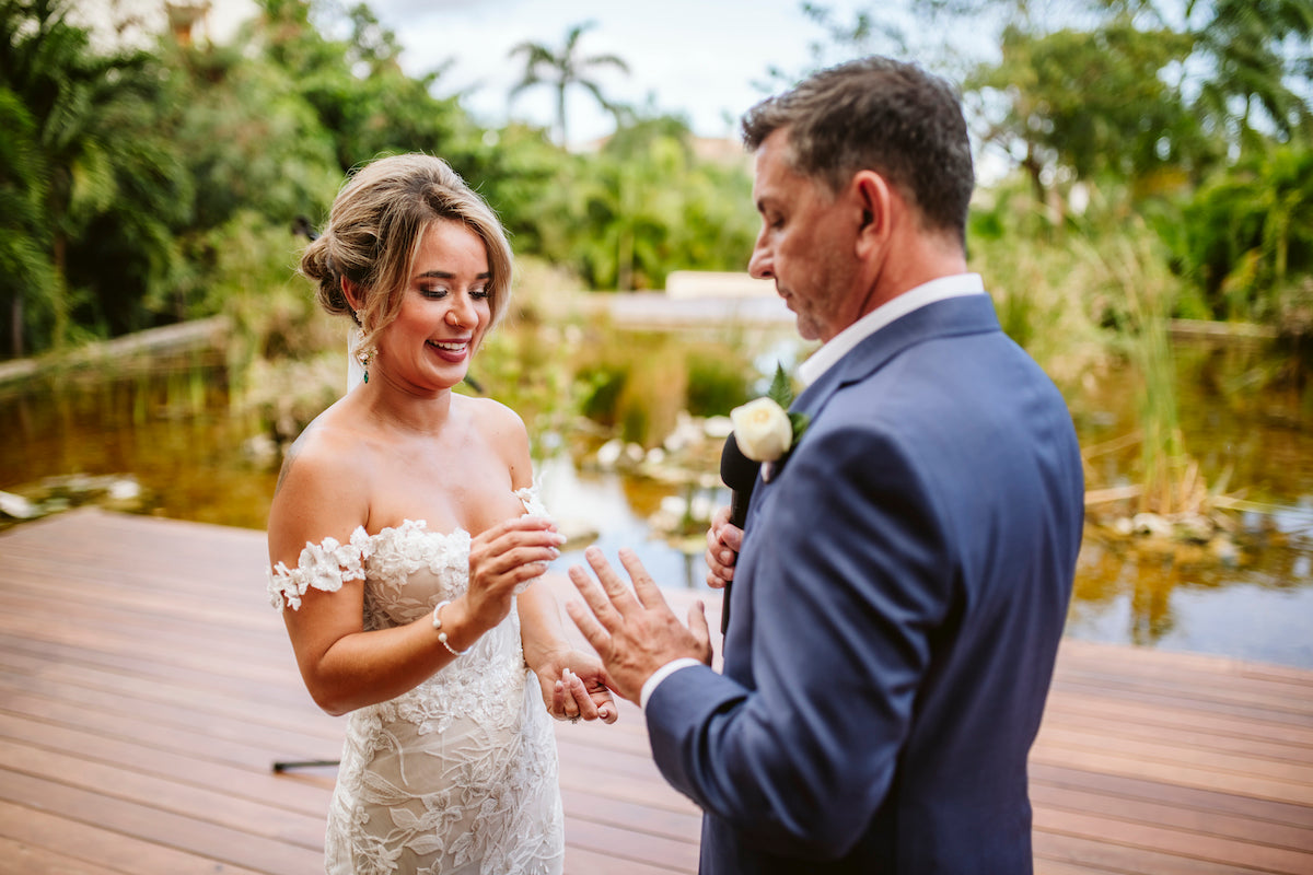 Bride smiles as she slides the ring onto the groom's finger during a ceremony at Secrets Akumal