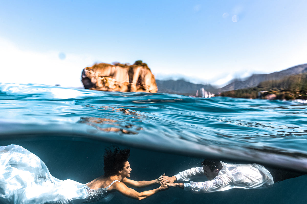 Bride and groom hold hands underwater in the ocean during a trash the dress photoshoot