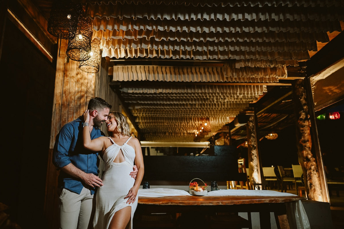 Couple embraces in a candlelit open-air restaurant with woven lamps at Viceroy Riviera Maya