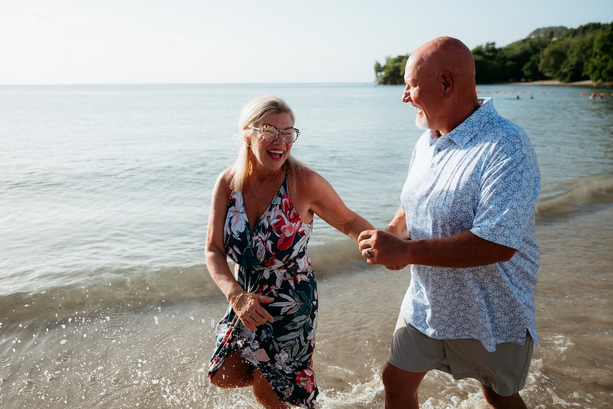 Laughing couple holds hands as they splash in the shallows during a photoshoot at Zoëtry Marigot Bay St. Lucia