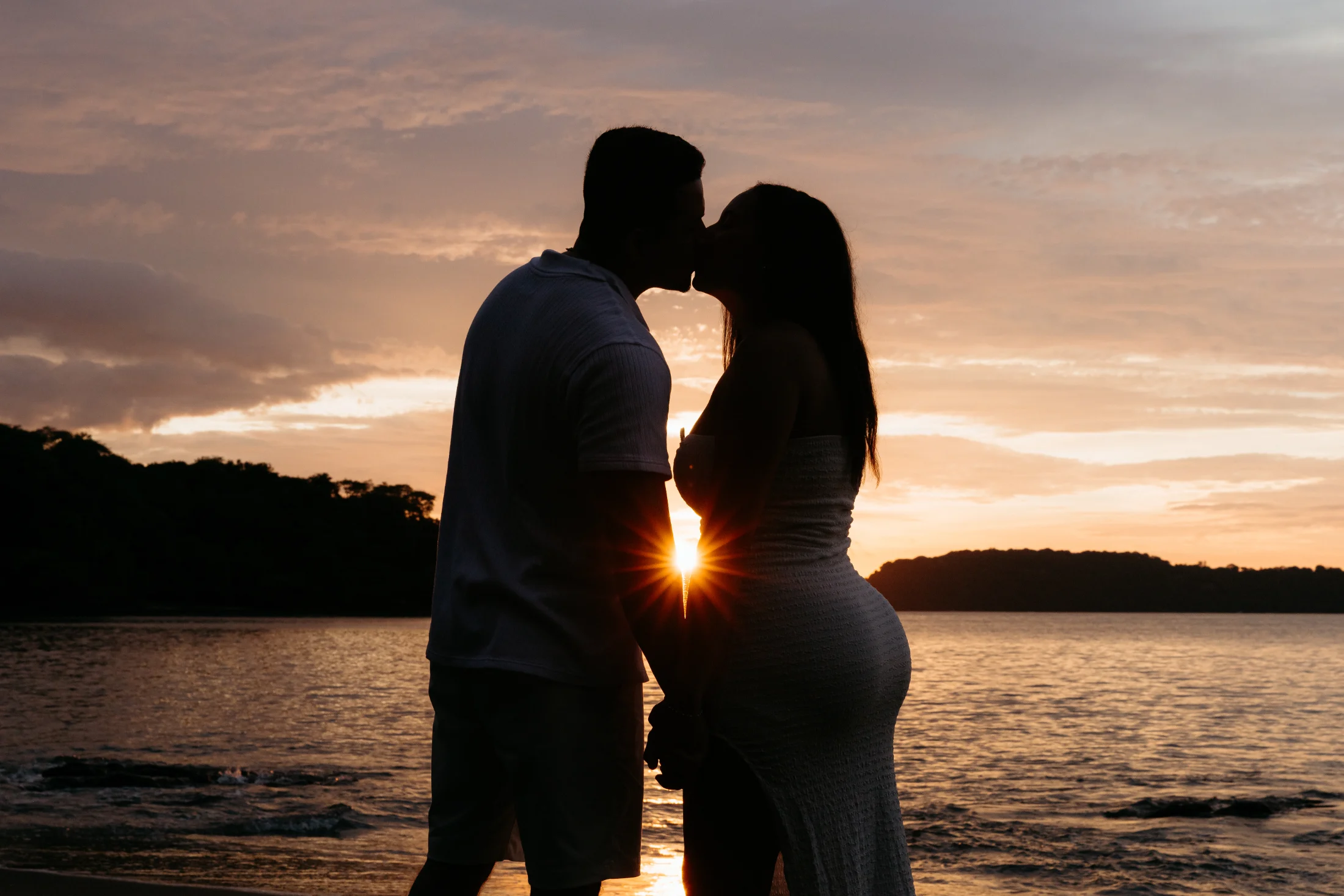 Couple kissing against the sunset by the sea