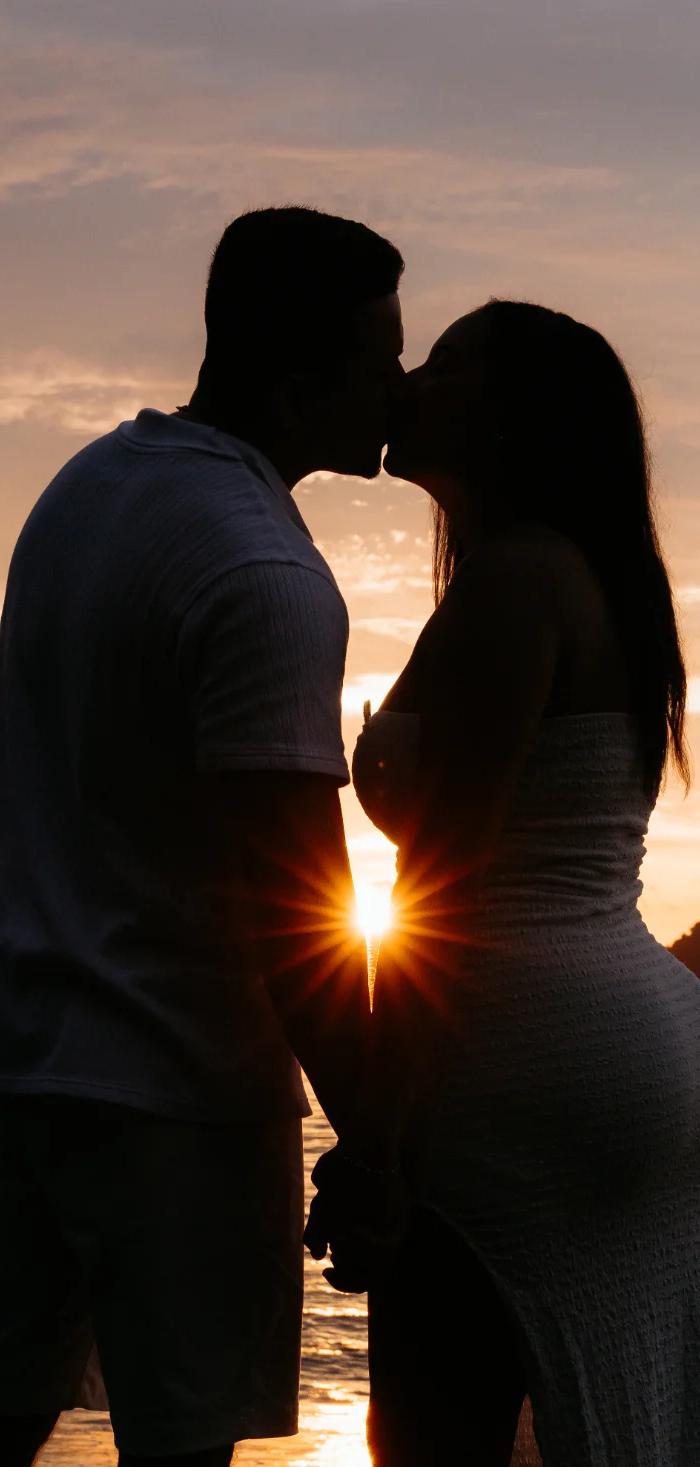 Couple kissing against the sunset by the sea